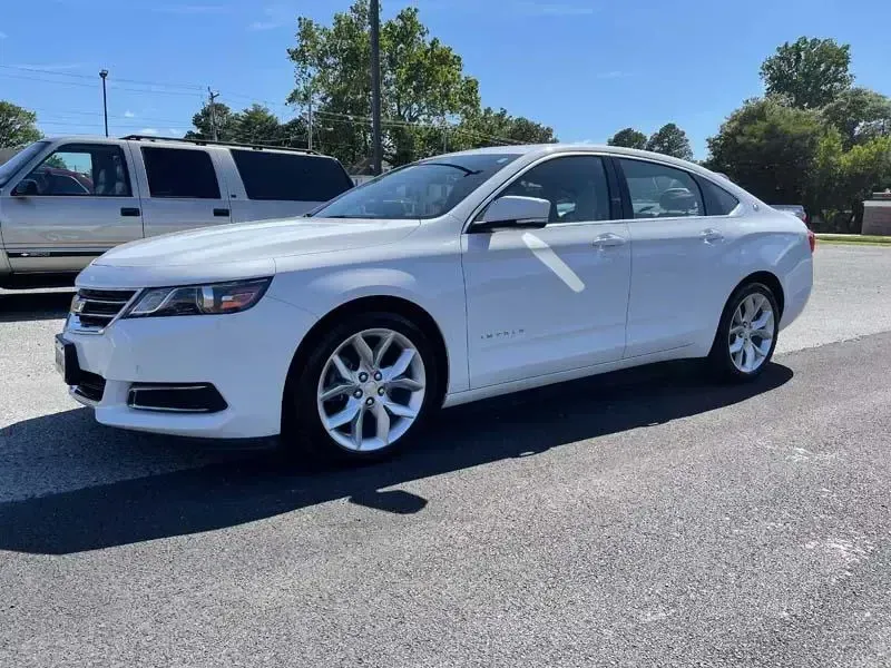 A white chevrolet impala is parked on the side of the road.