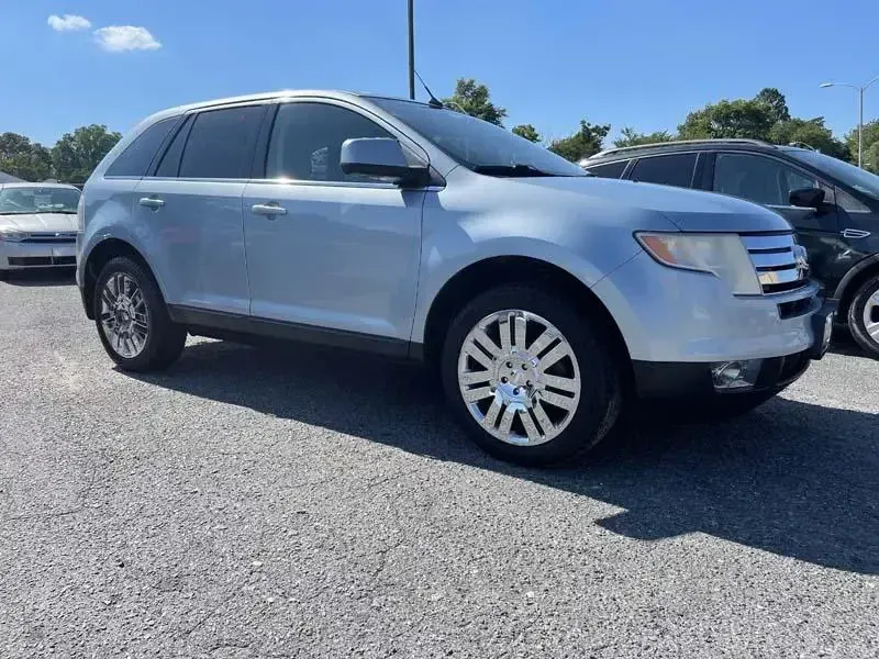A silver ford edge is parked in a parking lot.