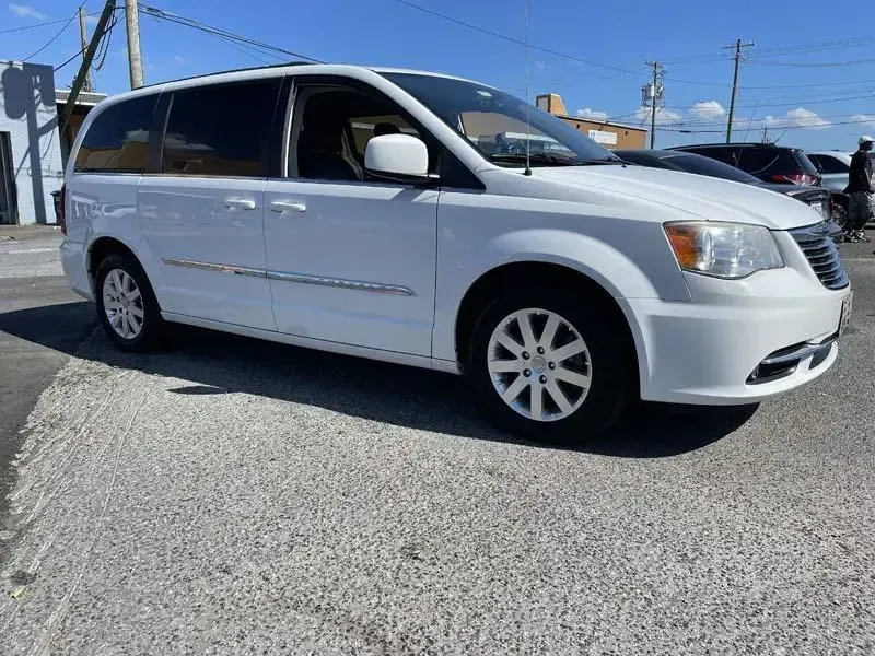 A white minivan is parked on the side of the road.