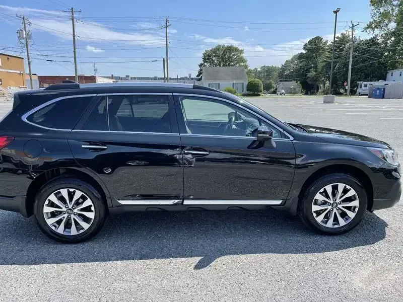 A black subaru outback is parked in a parking lot.