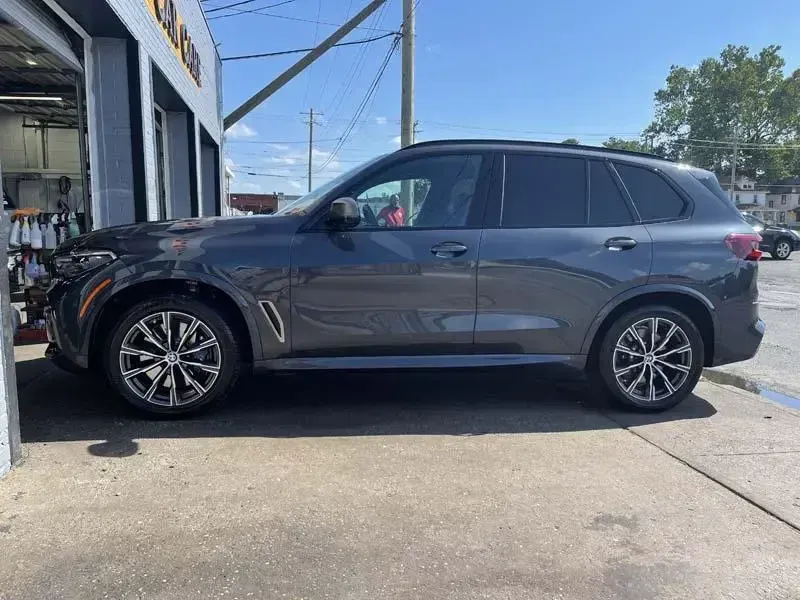 A bmw x5 is parked in a parking lot in front of a garage.