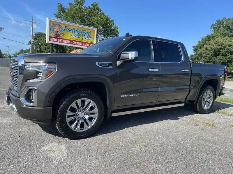 A gray pickup truck is parked on the side of the road in front of a sign.