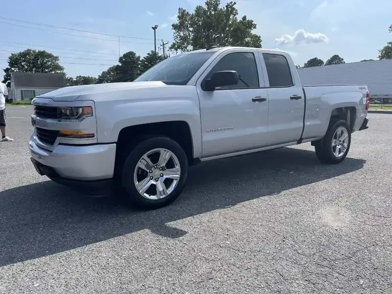 A silver chevrolet silverado pickup truck is parked in a parking lot.