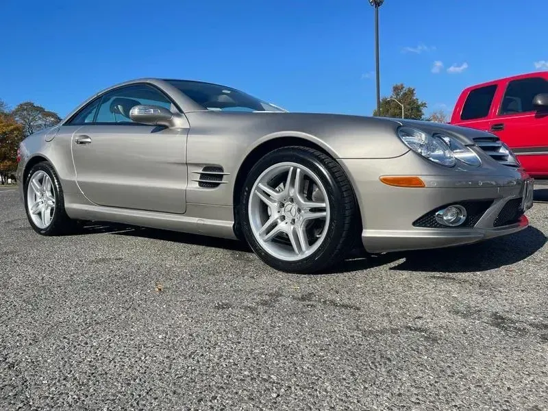 A silver sports car is parked in a parking lot next to a red truck.