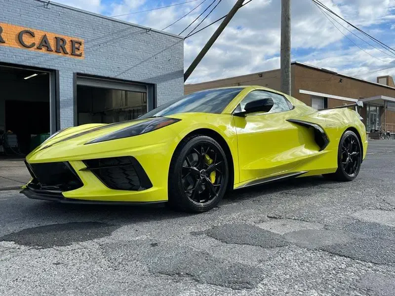 A yellow sports car is parked in front of a garage.