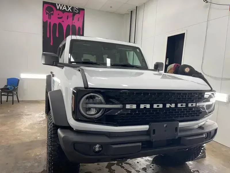 A white ford bronco is parked in a garage.