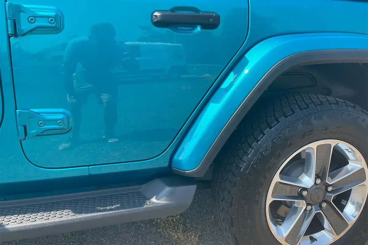 A blue jeep is parked on the side of the road.