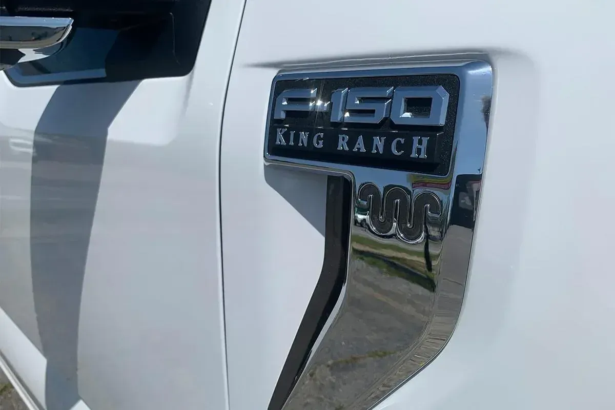 A white ford f150 king ranch truck is parked on the side of the road.