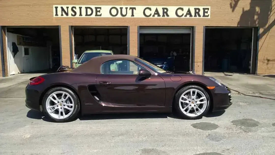 A purple sports car is parked in front of a building that says inside out car care.