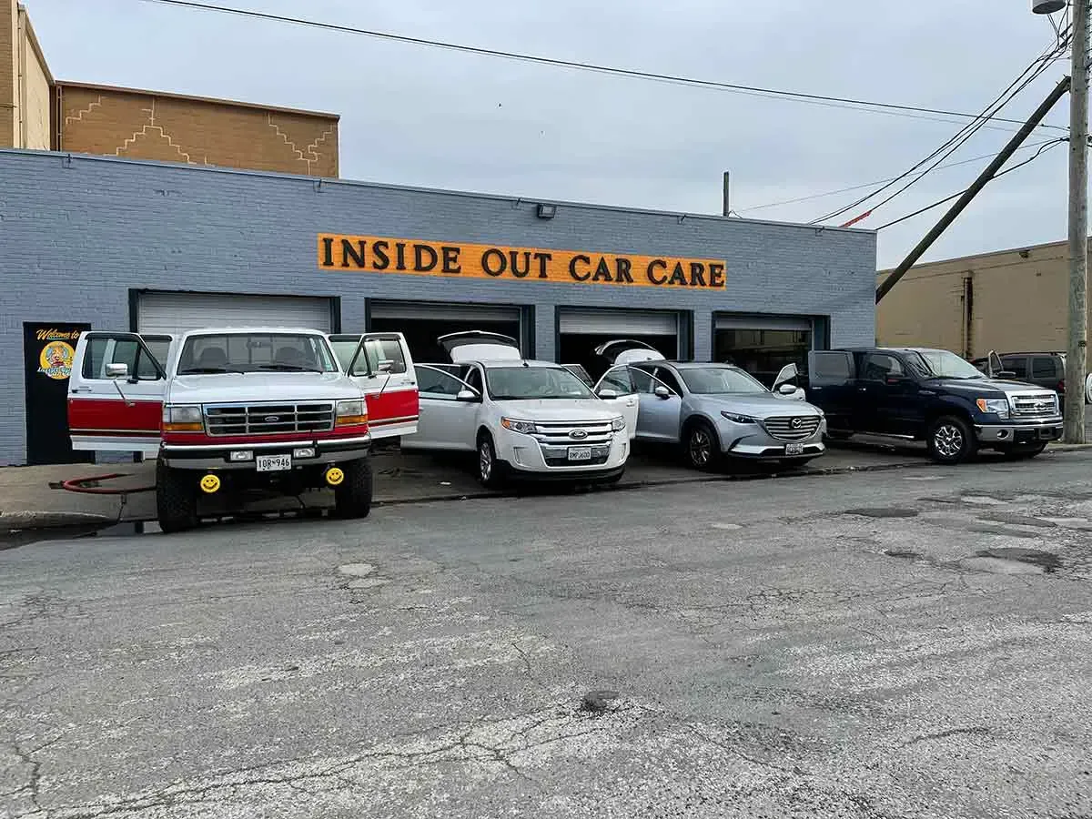 A row of cars are parked in front of a building that says inside out car care.