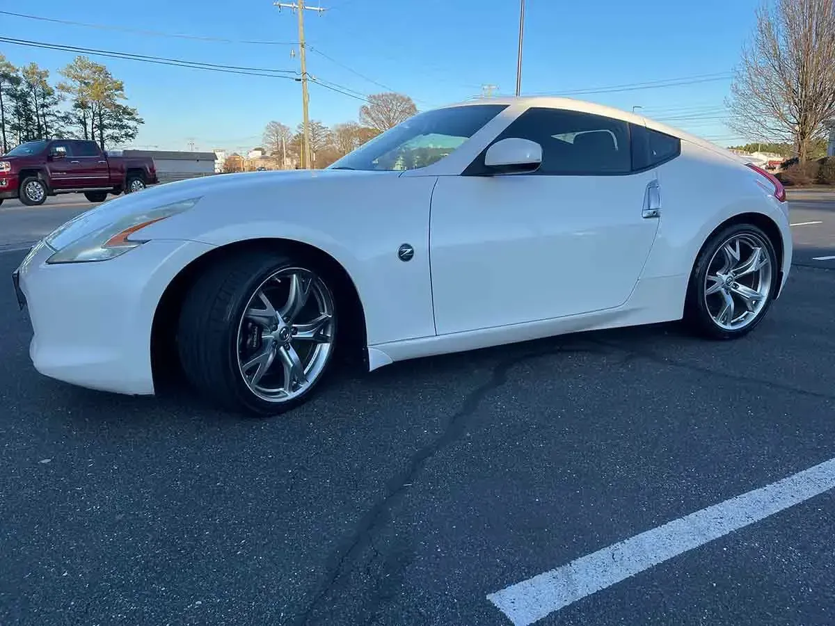 A white nissan 370z is parked in a parking lot.