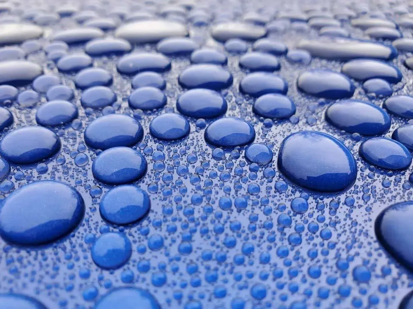 A close up of water drops on a blue surface.