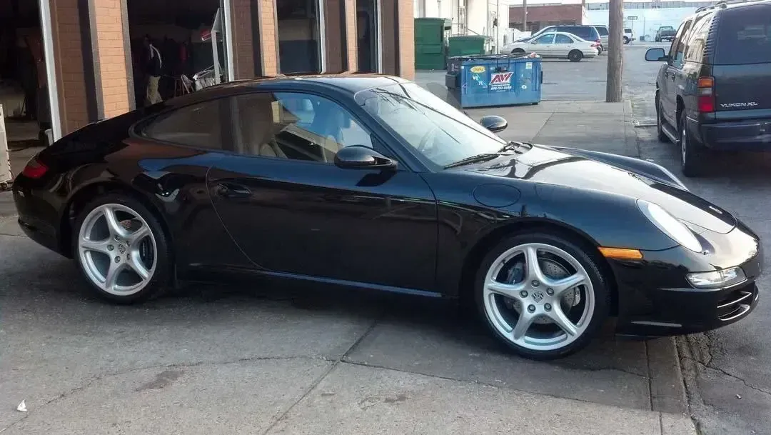 A black porsche 911 is parked in front of a garage