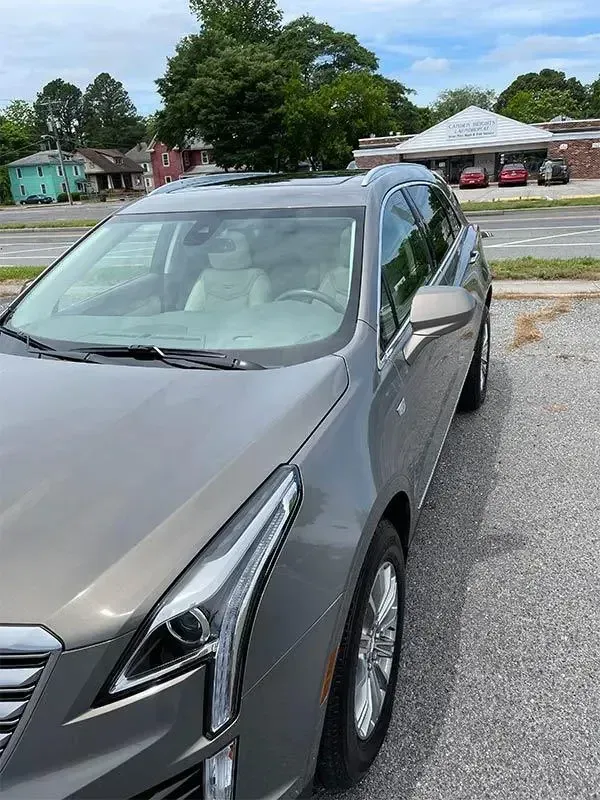 A gray car is parked on the side of the road.