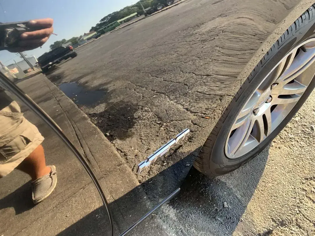 A person is standing next to a car in a parking lot