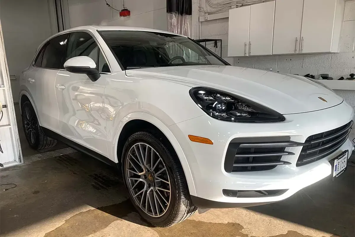 A white porsche cayenne is parked in a garage.