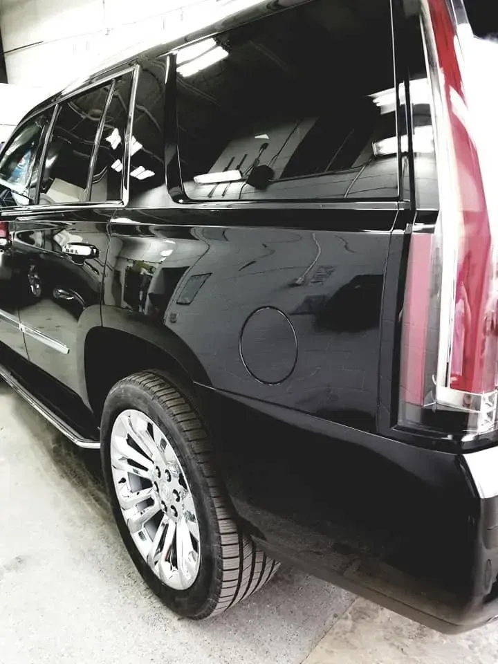 Black Cadillac SUV, shiny finish, chrome wheels, gas cap visible.