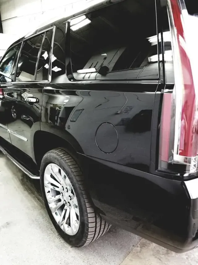 Black Cadillac SUV, shiny finish, chrome wheels, gas cap visible.