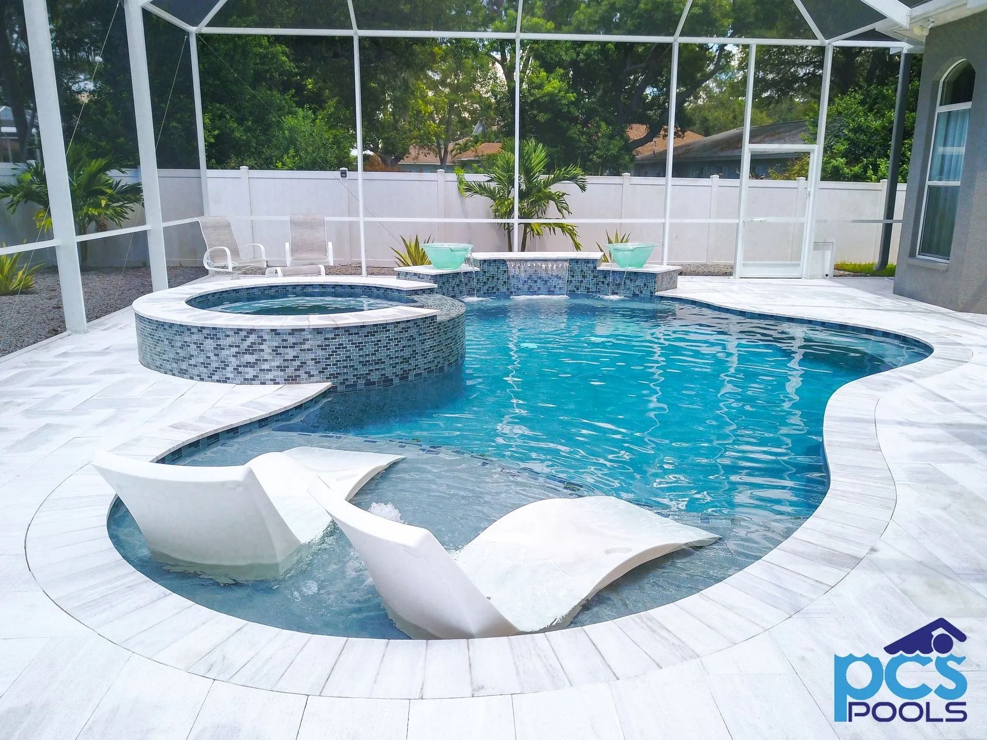 Pool with spa and lounge chairs inside, under a screened enclosure. Blue water, white accents.