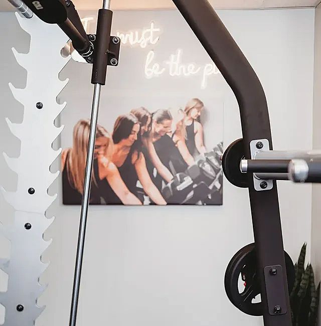 Smith machine in a gym setting, with motivational artwork on the wall.