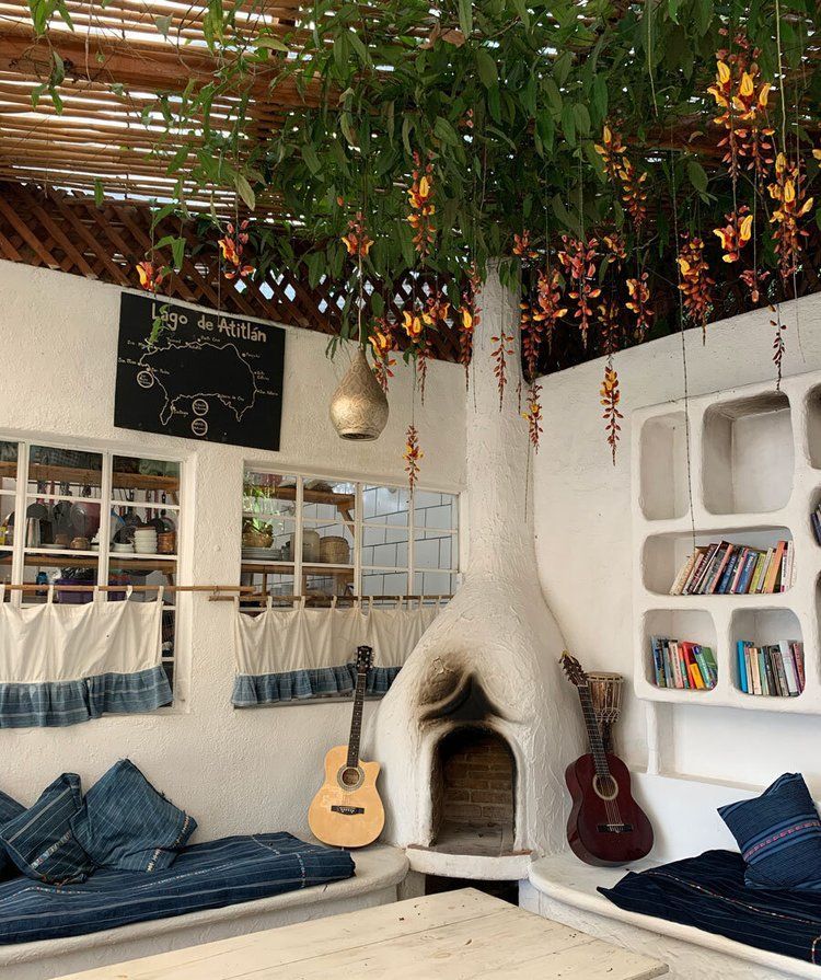 Cozy cafe with white walls, built-in seating, guitars, fireplace, and hanging vines.