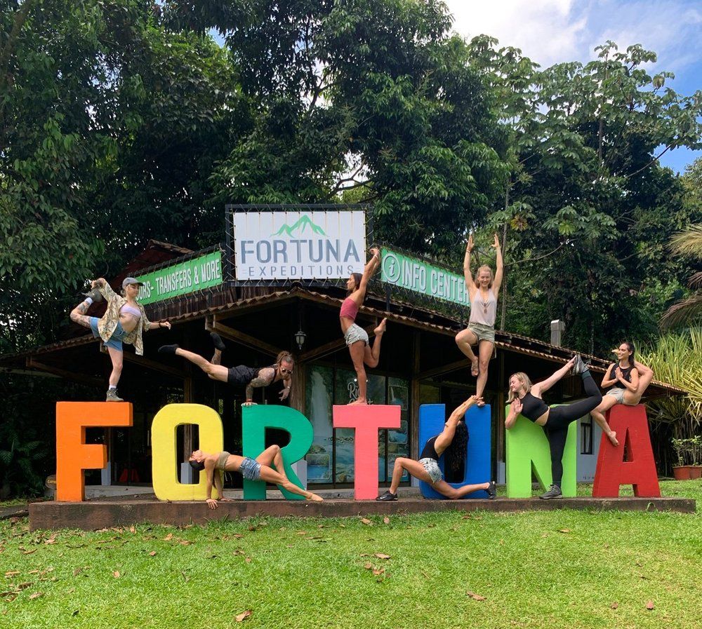 People posing in acrobatic positions on large colorful letters that spell 