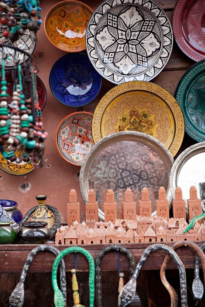 Display of colorful ceramic plates, trays, and handcrafted trinkets in a shop.
