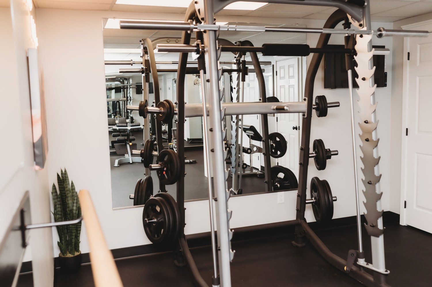 Gym interior with weight rack, weights, and a large mirror.