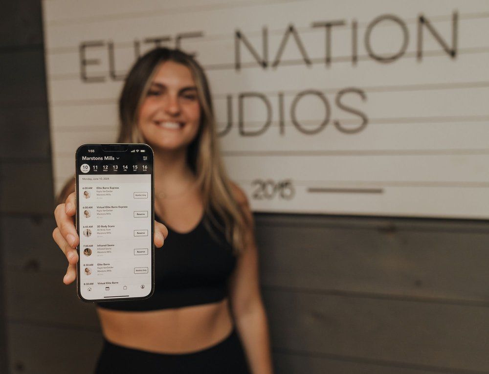 Woman in workout clothes holding a phone, smiling in front of 