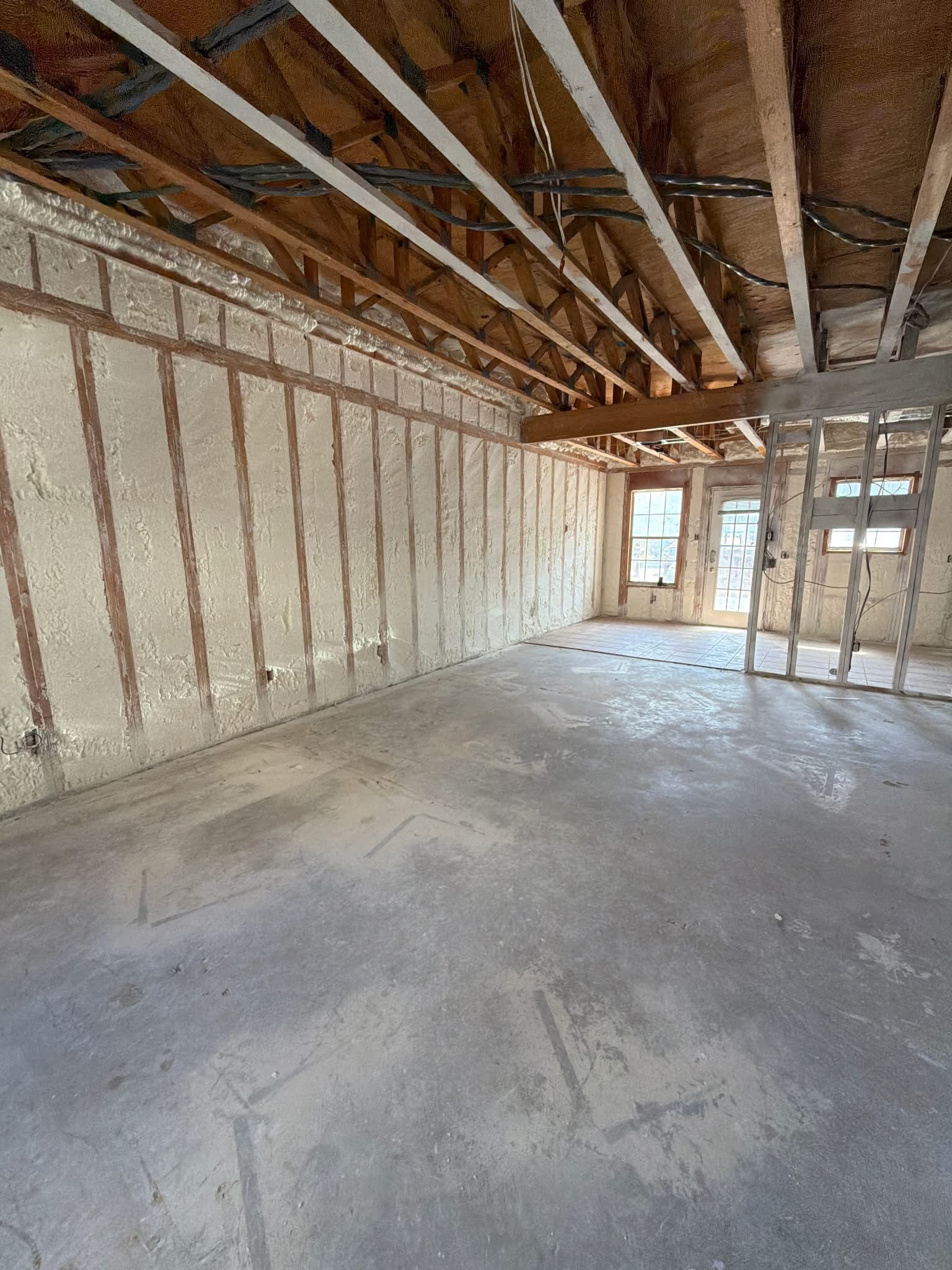 Unfinished room with exposed wooden framing, insulation, and concrete floor under construction.