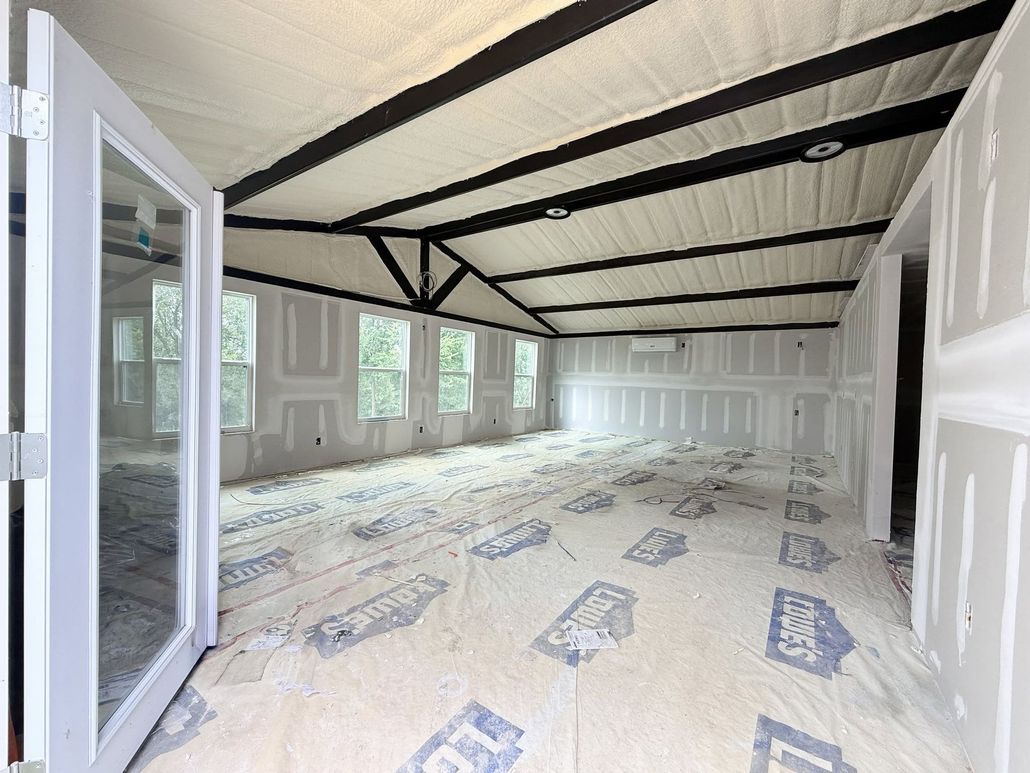 Spacious enclosed patio with open French doors, white walls, and a striped canopy ceiling.