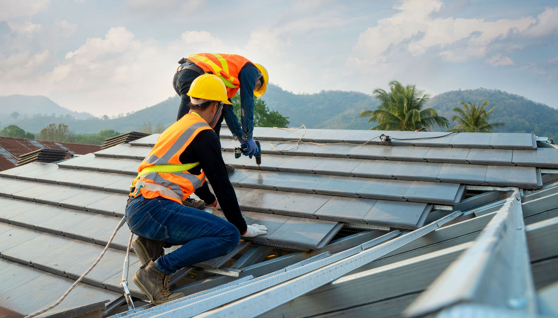 Two workers in safety gear installing solar panels on a rooftop.