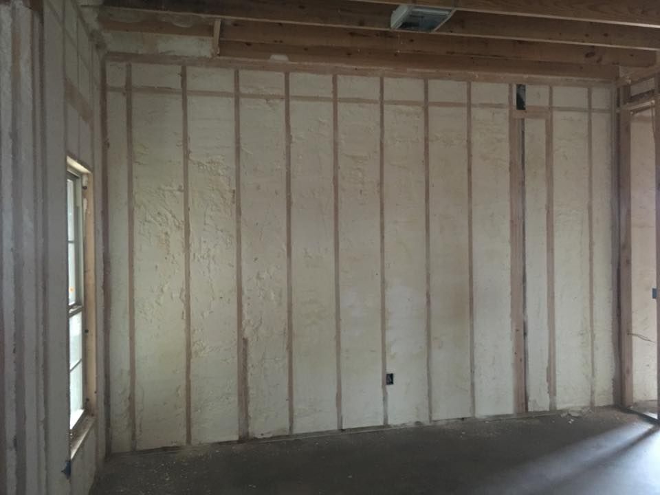 Interior wall of a building under construction, filled with spray foam insulation between wooden studs.