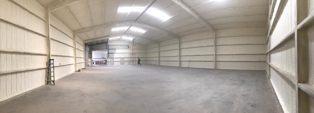 Empty warehouse interior with concrete floor and metal walls and roof.