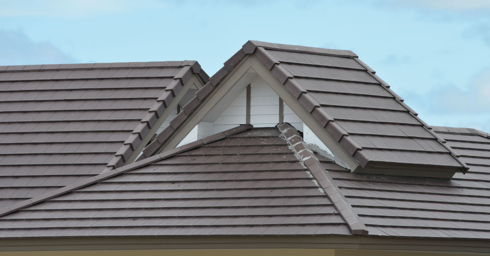 Brown tiled roof with triangular dormer. Blue sky in background.