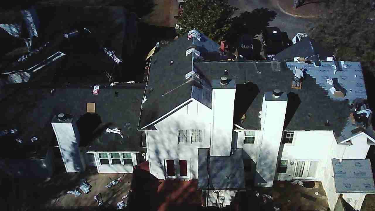 Aerial view of a white multi-story house with a complex dark-shingled roof and several chimneys.