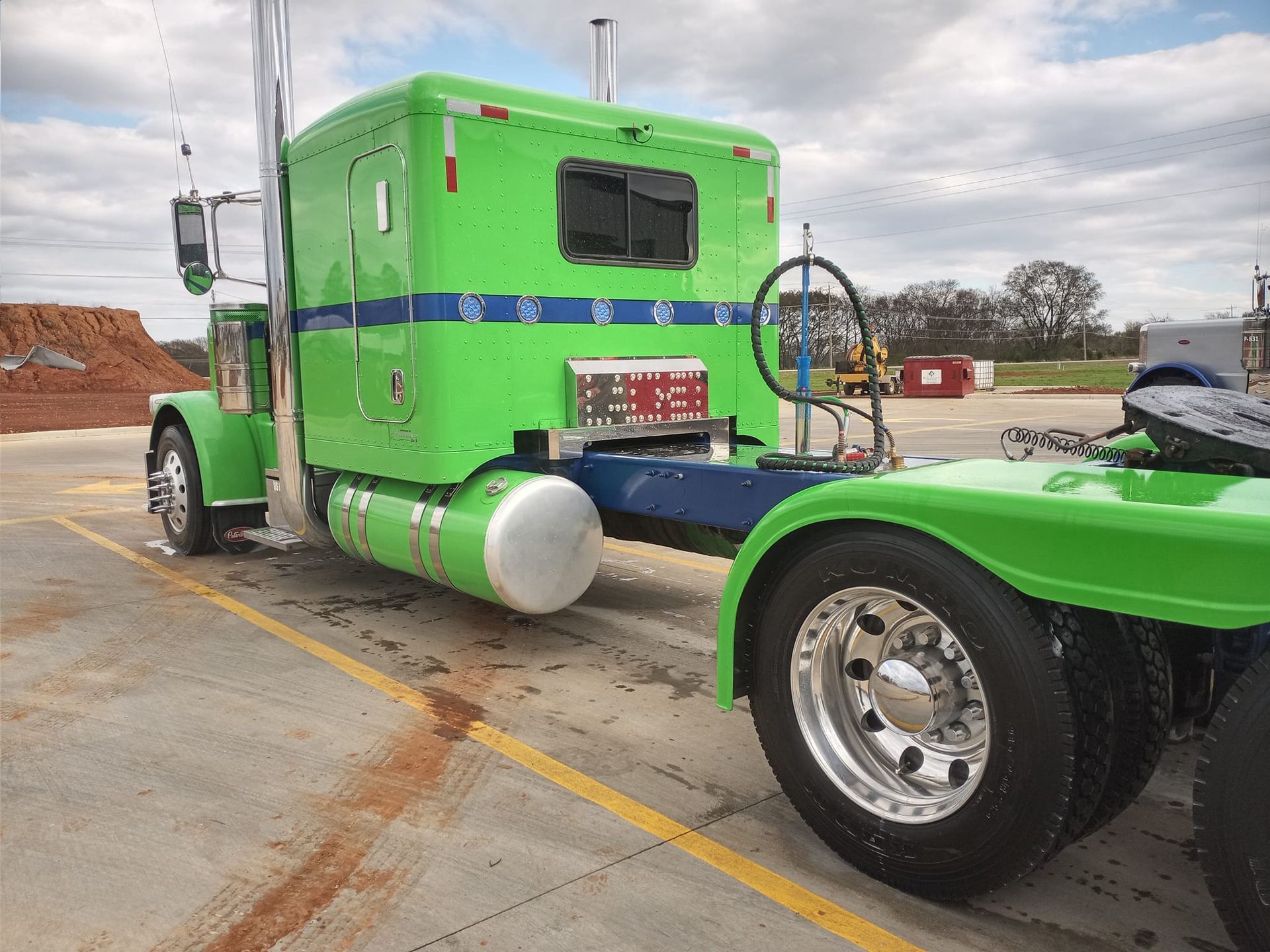 a green semi truck is parked in a parking lot .