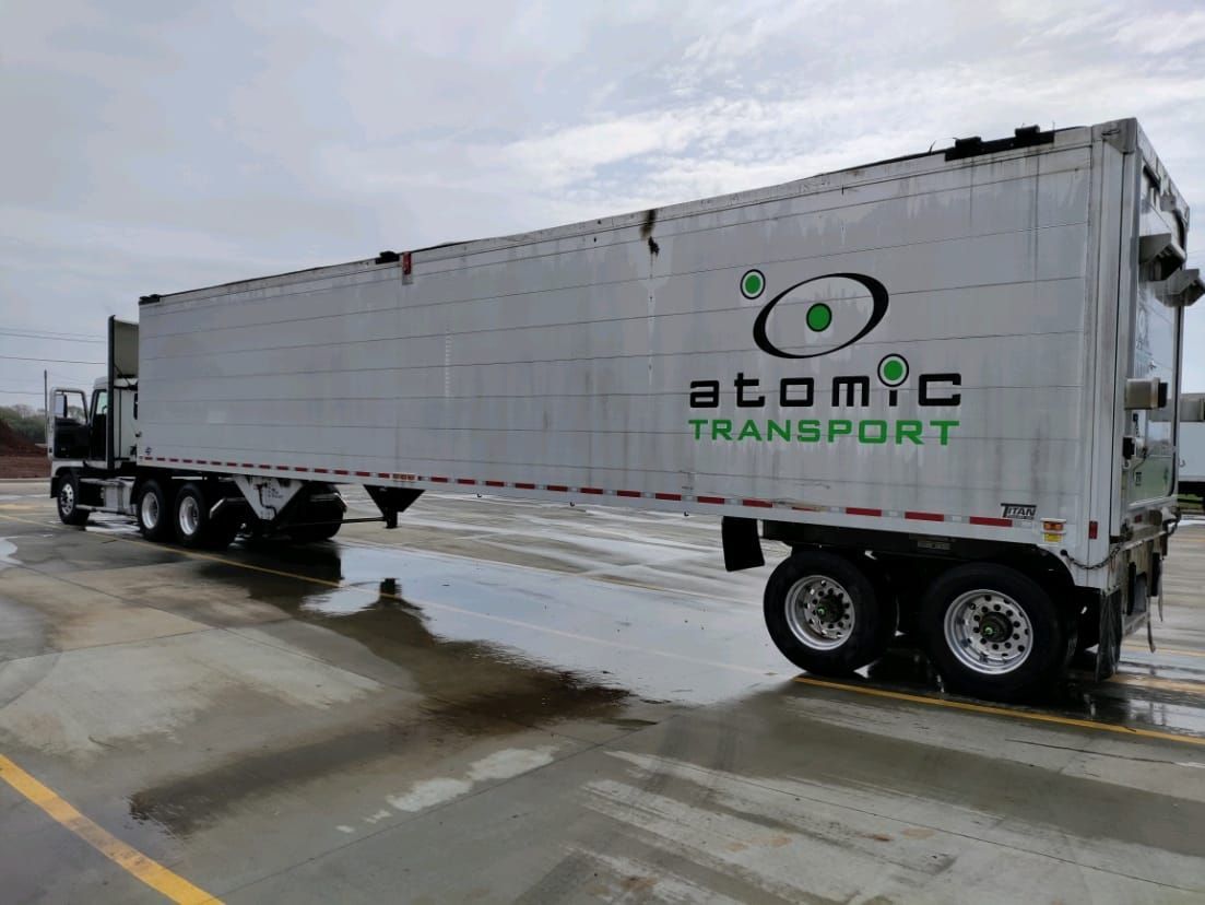 a semi truck from atomic transport is parked in a parking lot