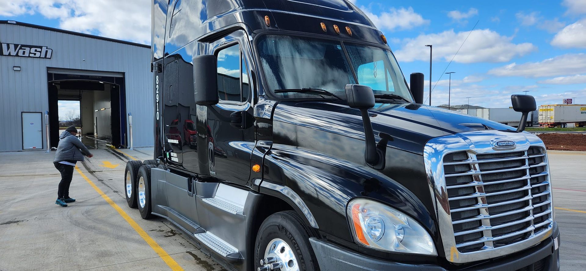 a black semi truck is parked in a parking lot in front of a building .