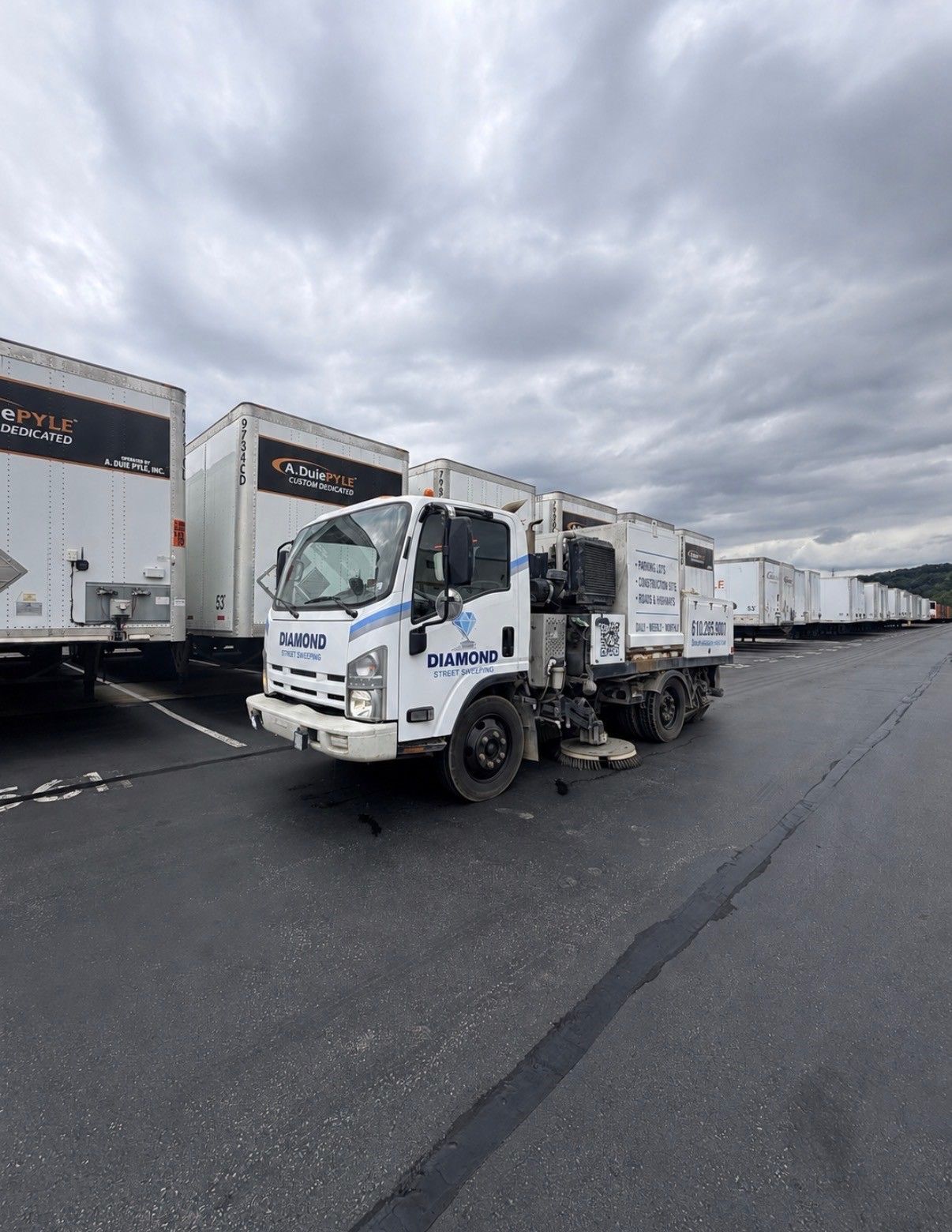 White refrigerated trucks parked in a lot under a cloudy sky, with one truck in the foreground.