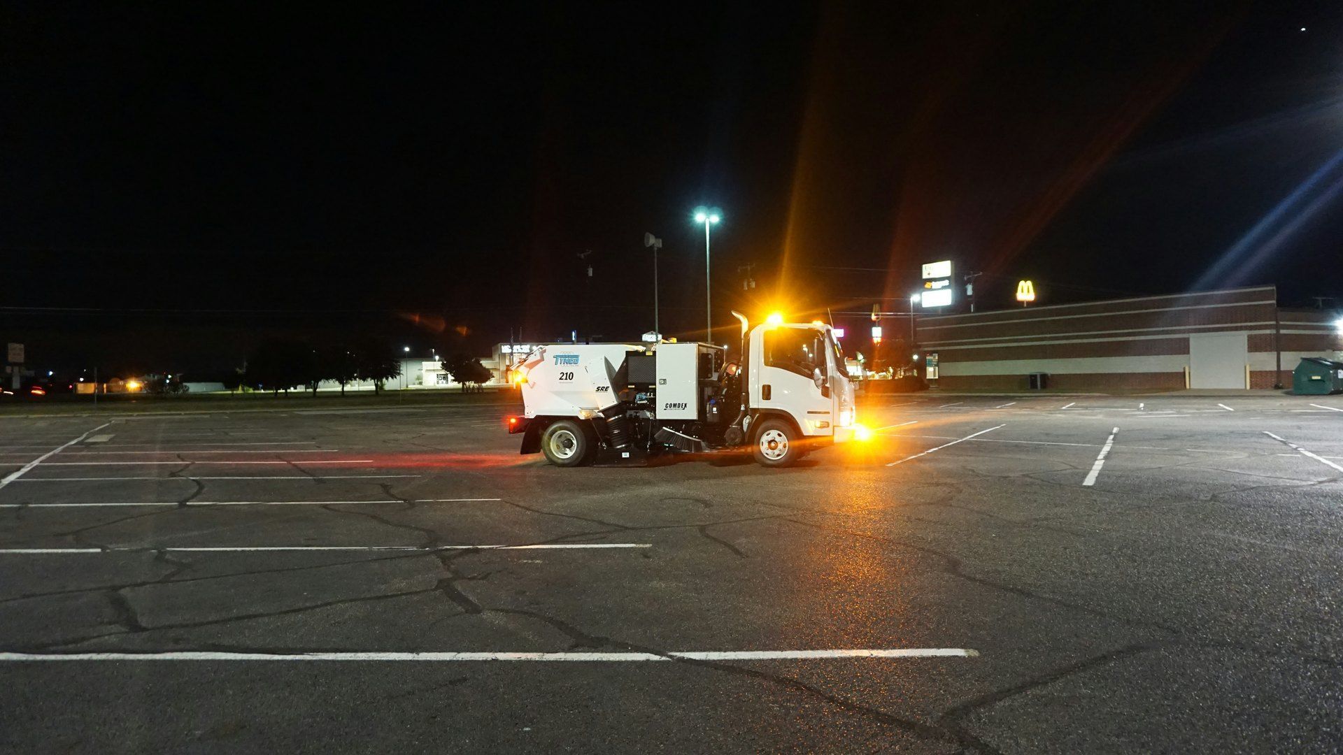 Utility truck with flashing amber lights in a dark parking lot at night