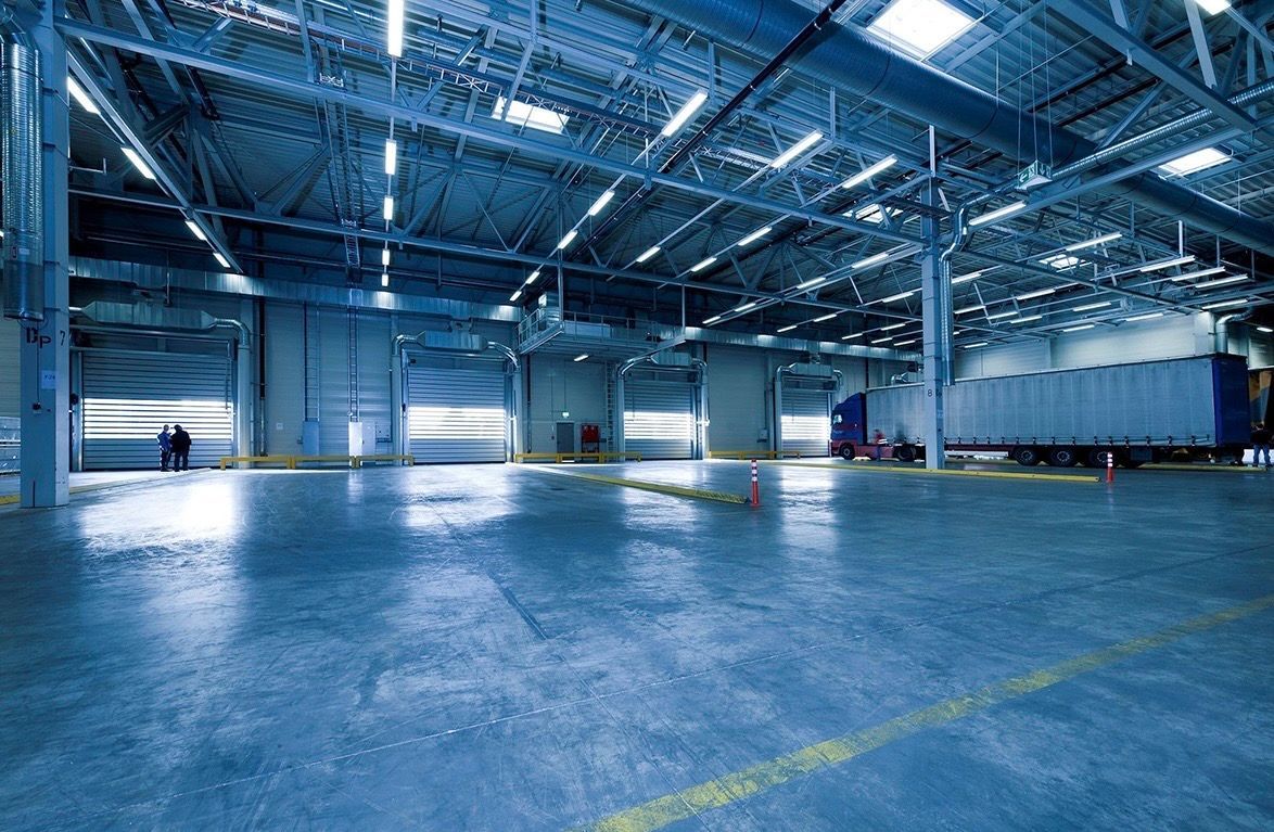 Empty blue-lit warehouse interior with polished concrete floor and high ceiling lights