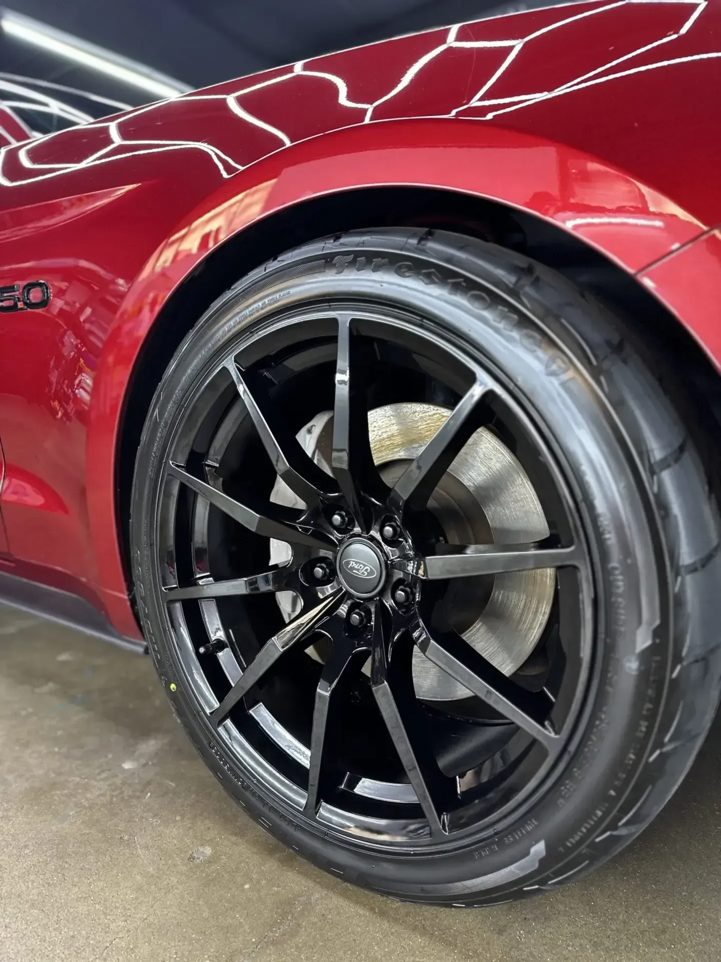 Black alloy wheel on a red sports car with a clear coat finish.