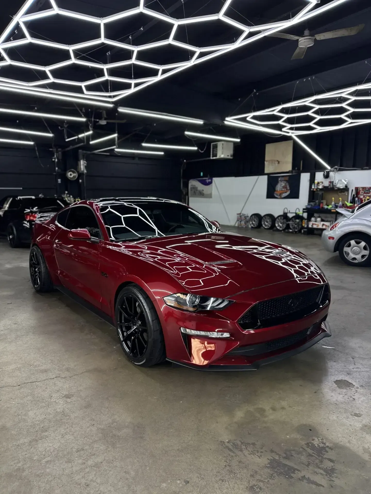 Burgundy Ford Mustang sports car in a well-lit garage with black accents.