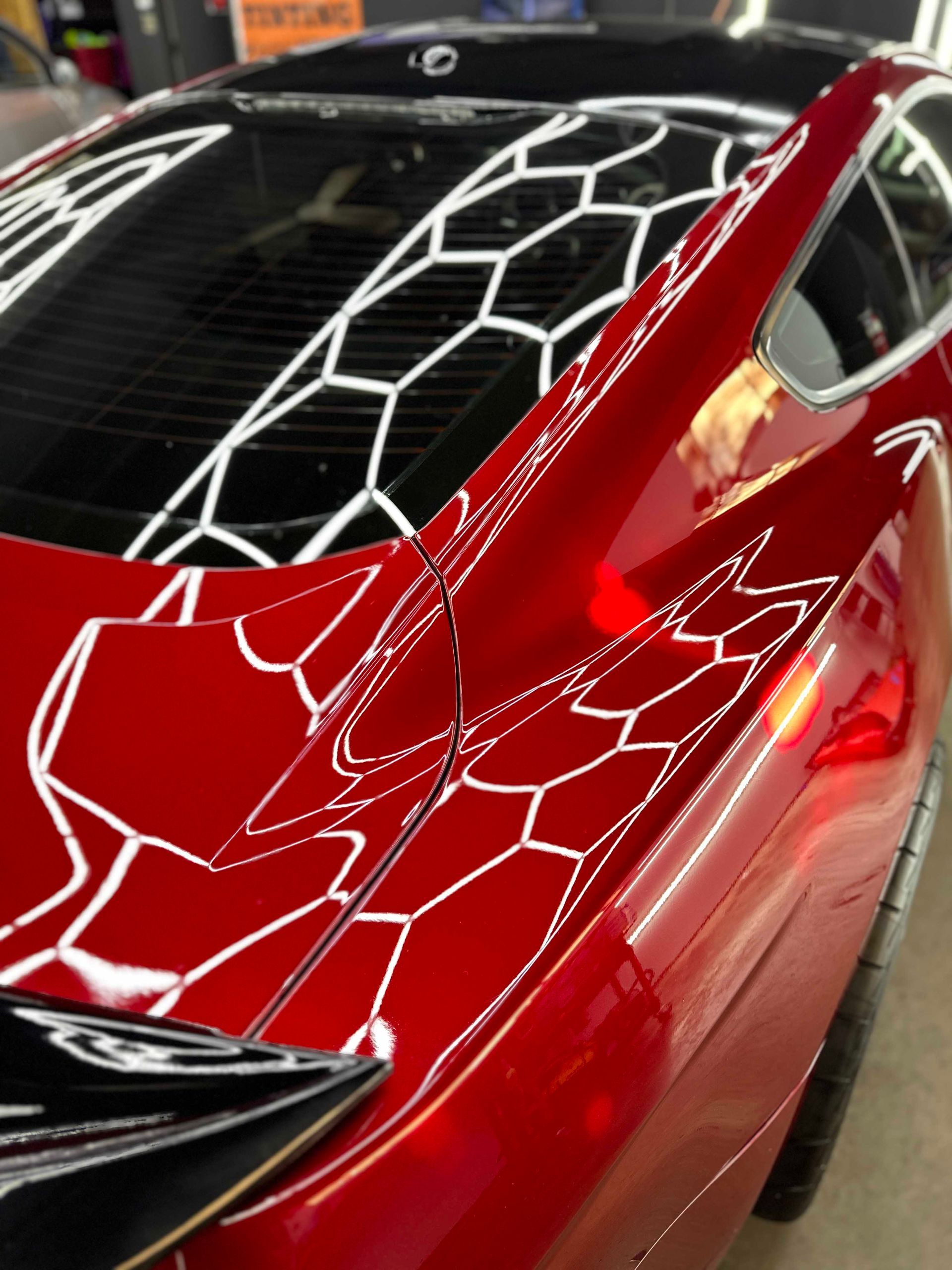 Red car with a white geometric pattern on the rear window and body.