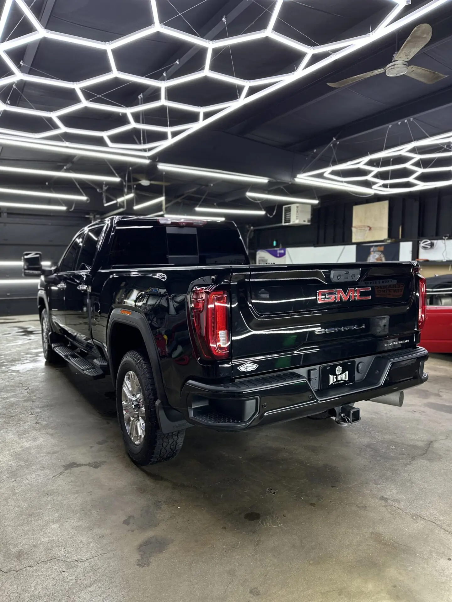 Black GMC truck parked under hexagonal lights.