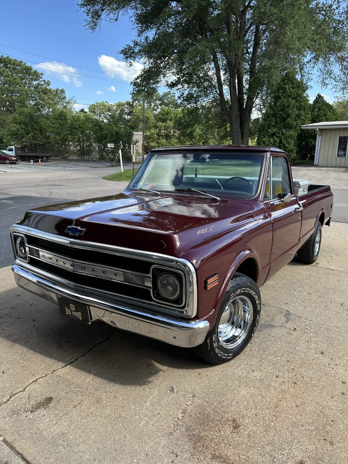 Maroon Chevrolet C10 pickup truck parked on asphalt, sunny day. Chrome accents, vintage style.