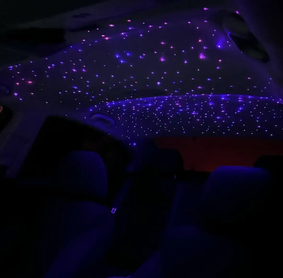 Interior car ceiling with starry lights in purple and blue.