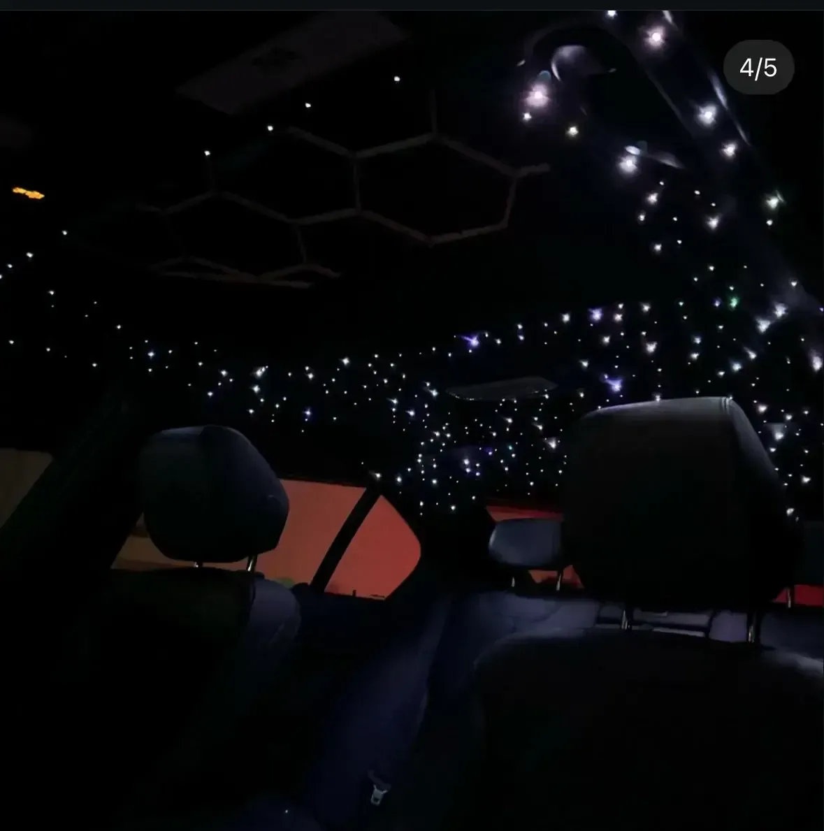 Interior car view with starry ceiling lights and black seats.
