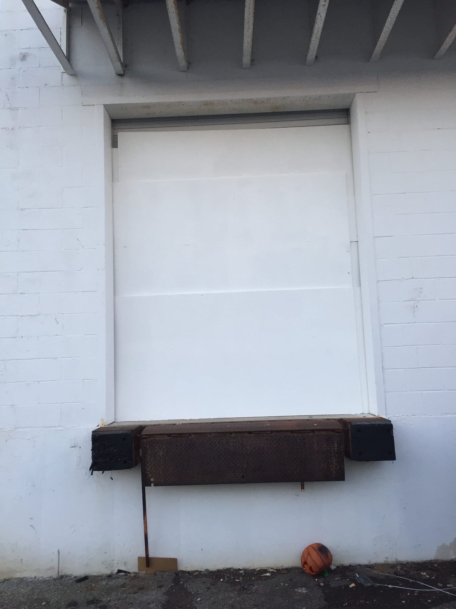 White brick building wall with a closed window and a dark wooden ledge beneath it.